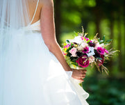 Bride holding a colorful bouquet with a blurred green background