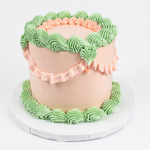 Load image into Gallery viewer, Two-tiered cake with pink and green frosting on a white background