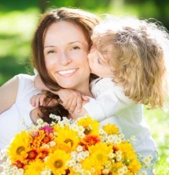 Child kissing Mother holding flowers